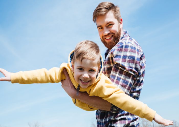 Close up of a young smiling father and his little son playing together in a city park