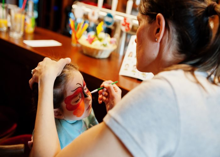 Preparing to Easter concept. Woman doing aqua makeup for baby girl.